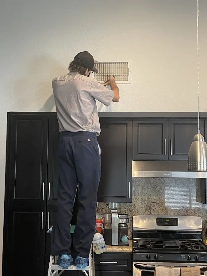 Technician inspecting an air vent during HVAC service in Monona